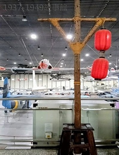 圖二 岡山的航空教育展示館[2]裡，有一根高約兩公尺的木柱，橫桿上掛著兩顆紅燈籠，這是抗戰期間，廣佈在重慶各制高點的無聲警報的複刻品，是為紀念抗日戰爭70周年、以及感念美國飛虎隊當年協助空防而製作的。